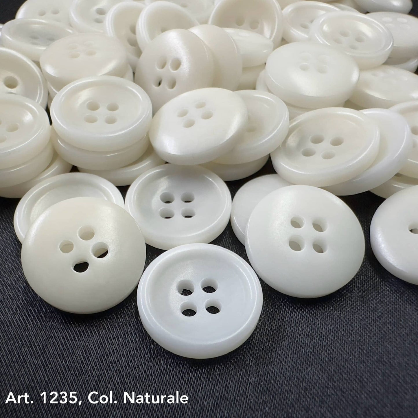 White Sustainable Sewing Buttons with four holes from Buttonology Inc. on a dark fabric background