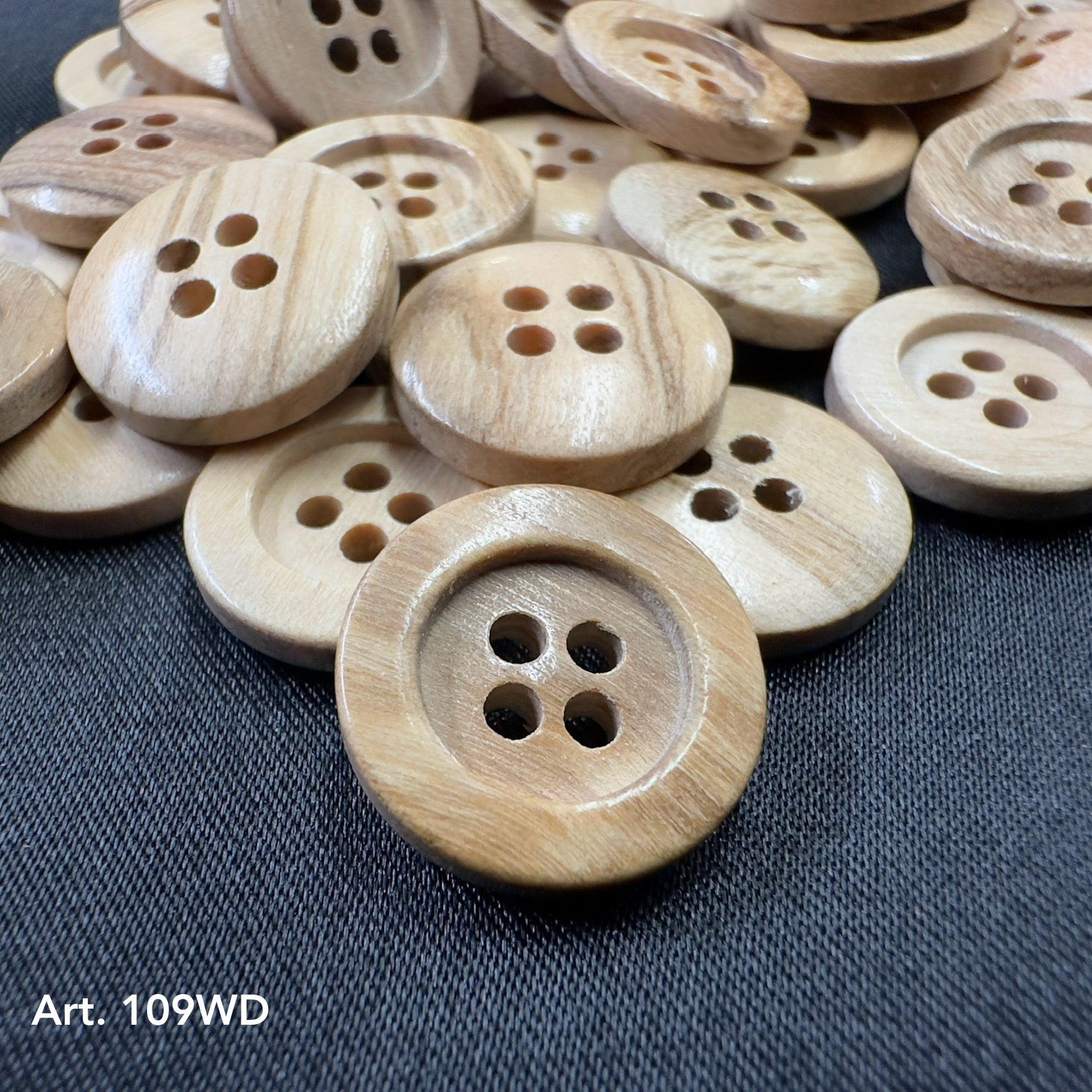 Natural olivewood sewing buttons with four holes by Buttonology Inc on dark fabric background