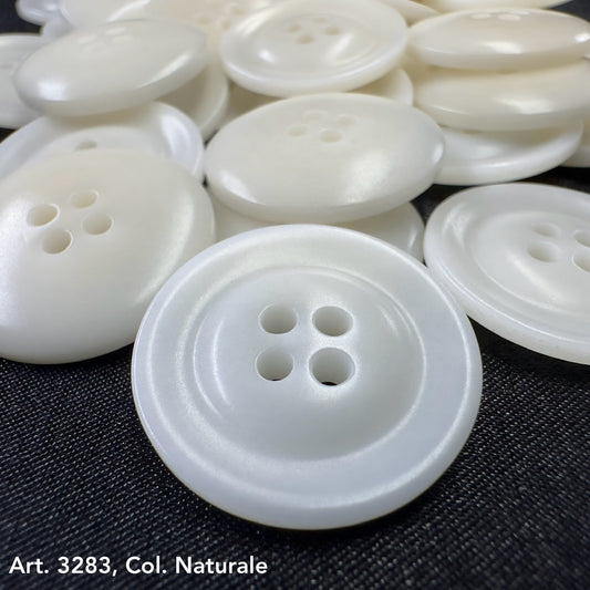 White eco-friendly garment buttons with four holes on dark fabric by Buttonology Inc