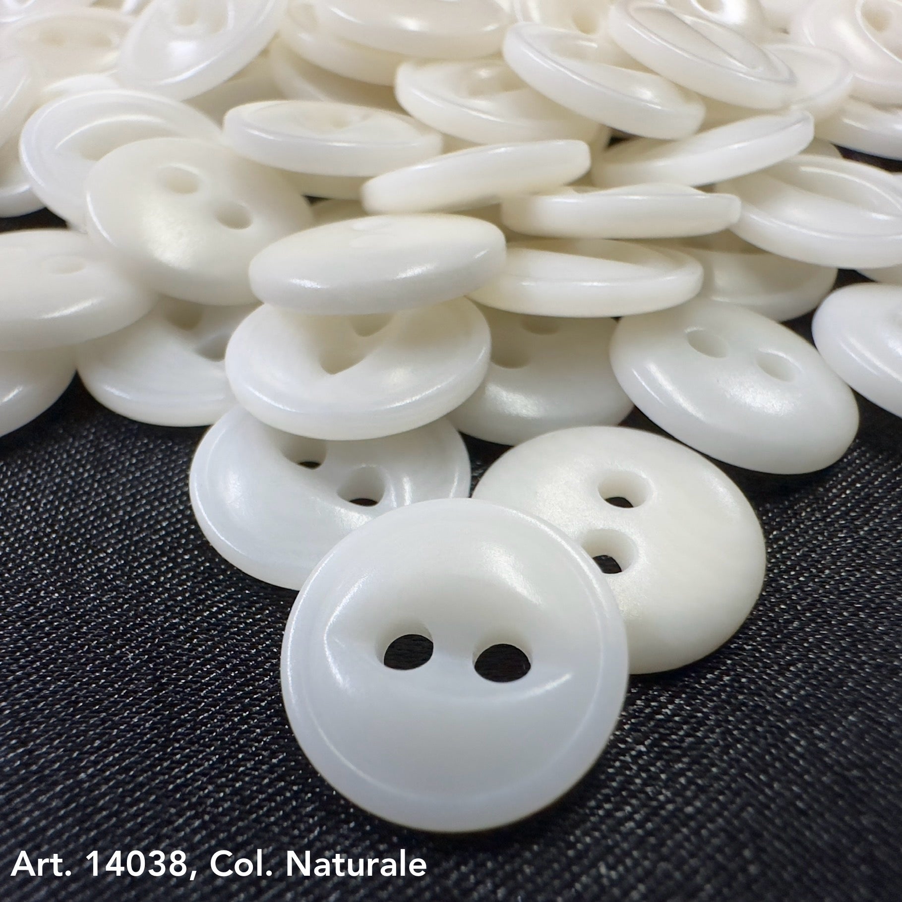 Premium corozo buttons two hole in natural color by Buttonology Inc scattered on dark fabric