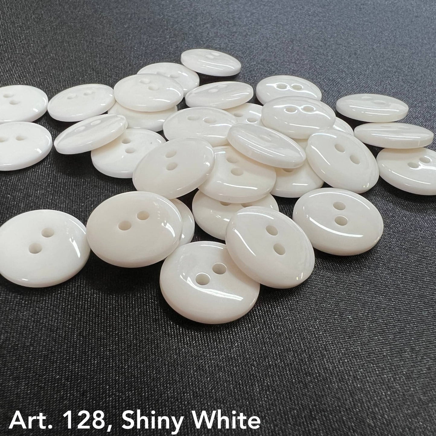 Premium white buttons by Buttonology Inc glossy shiny round two-hole buttons on black fabric