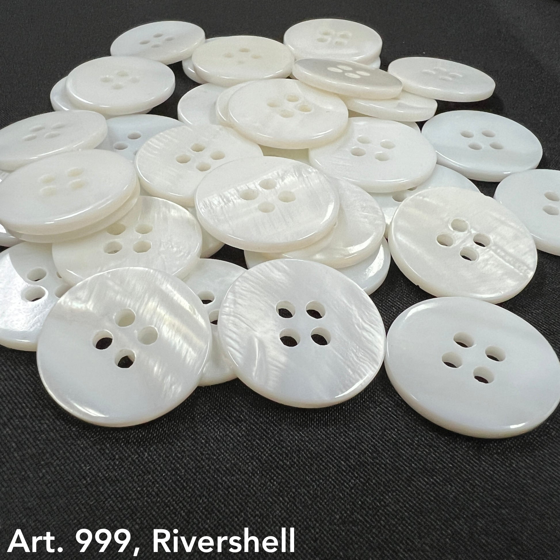 High-quality shell buttons in white with four holes from Buttonology Inc spread on black fabric