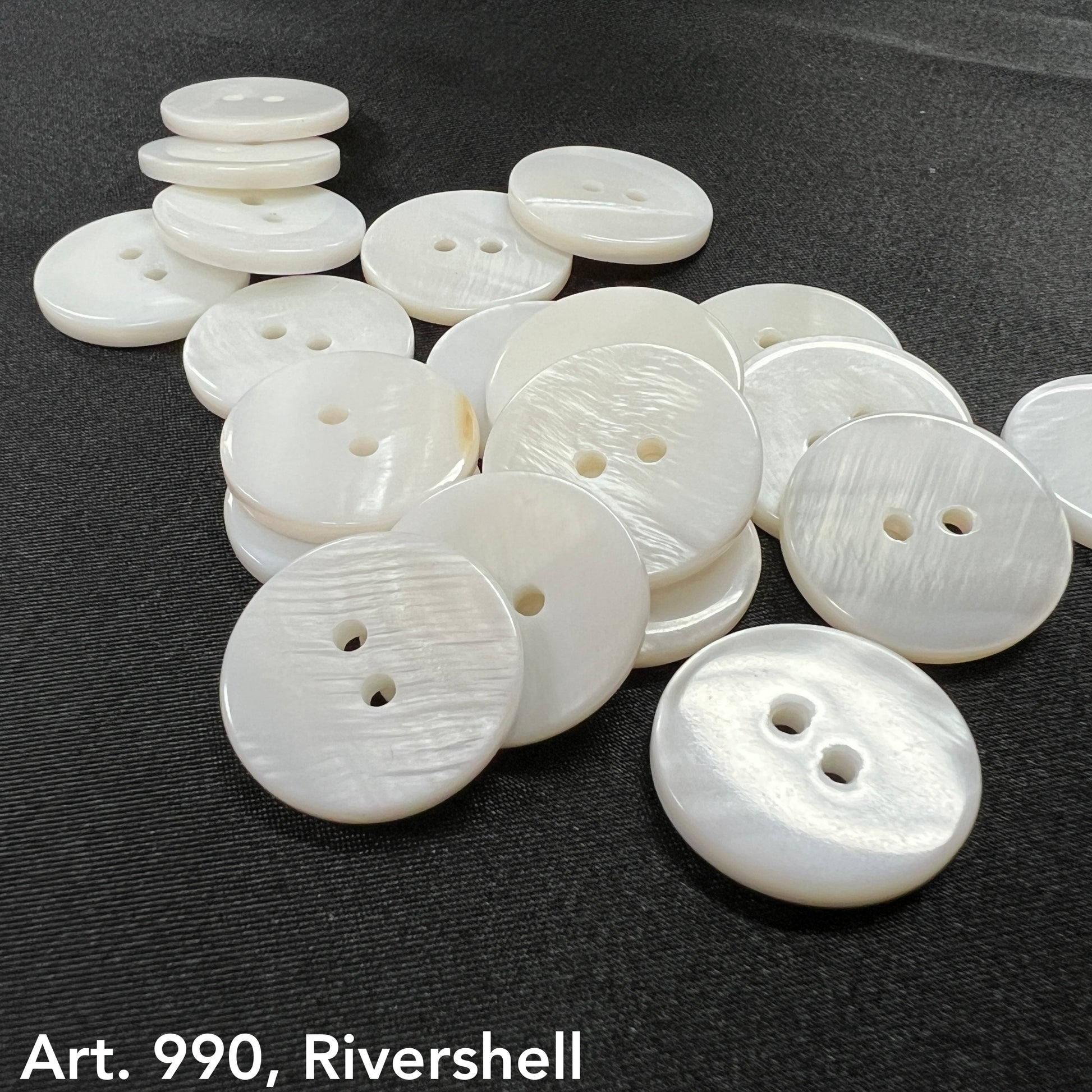 Premium shell buttons for sewing in white with two holes arranged on a black surface by Buttonology Inc