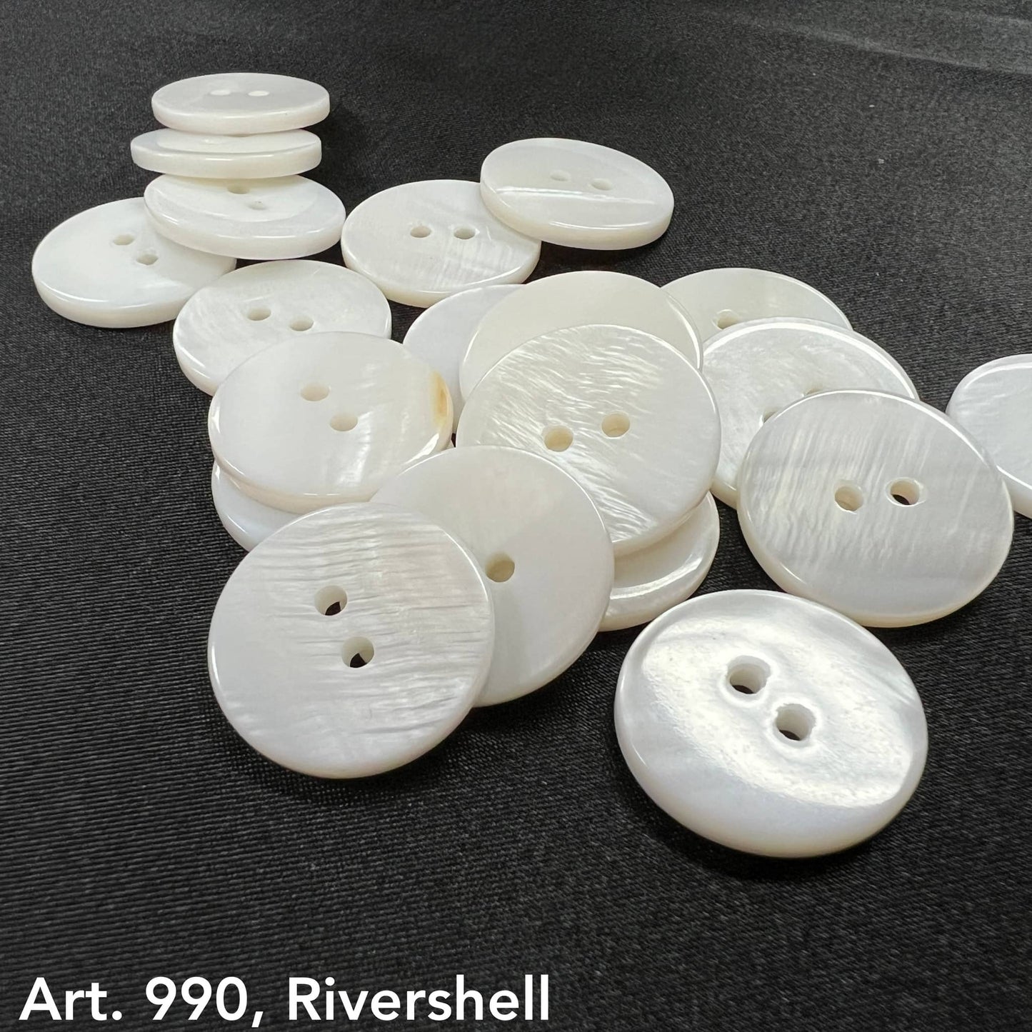 Premium shell buttons for sewing in white with two holes arranged on a black surface by Buttonology Inc