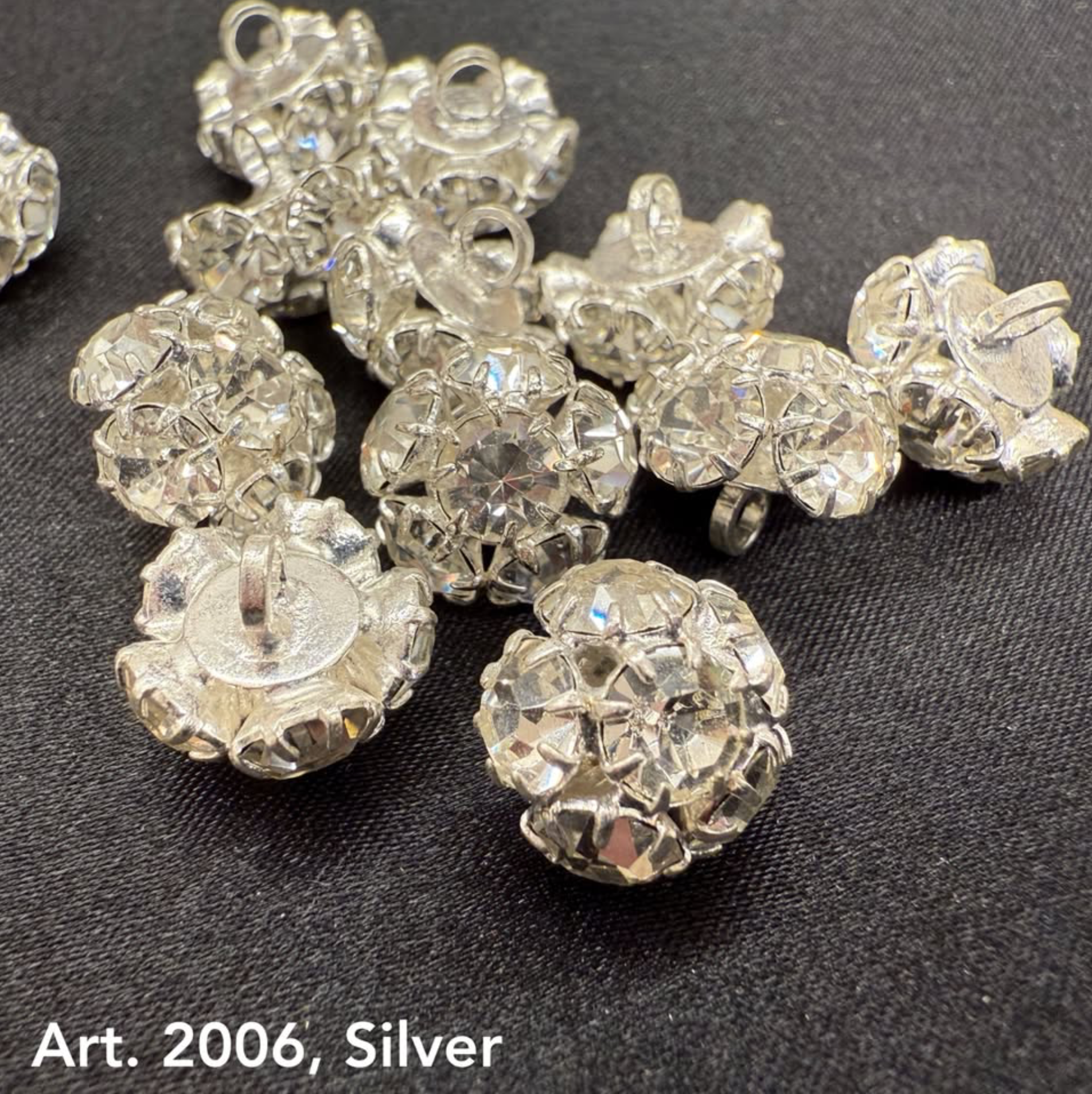 Buttonology Inc silver rhinestone buttons with sparkling faceted design on black fabric background