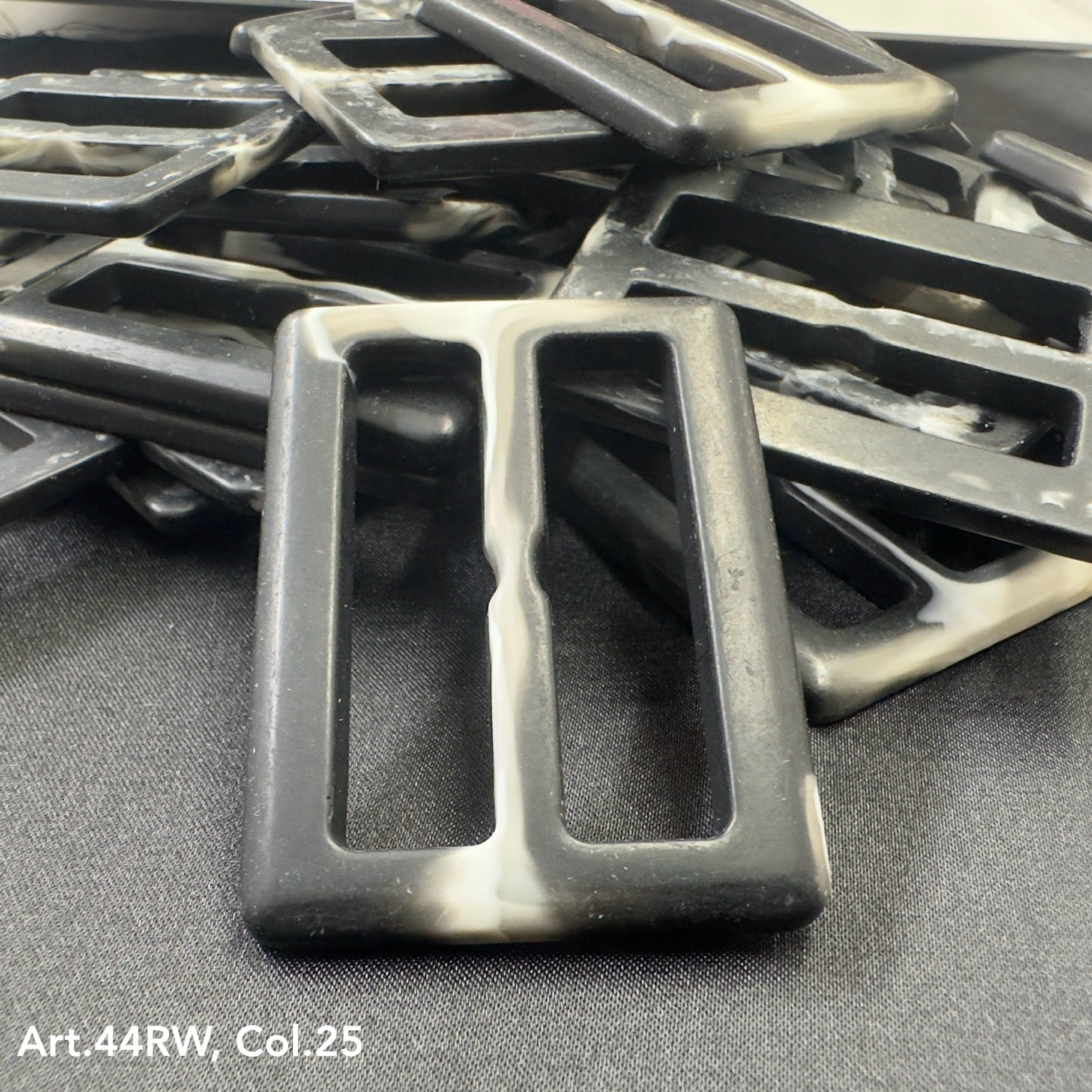 Black and white strong polyester buckles from Buttonology Inc arranged on a black surface