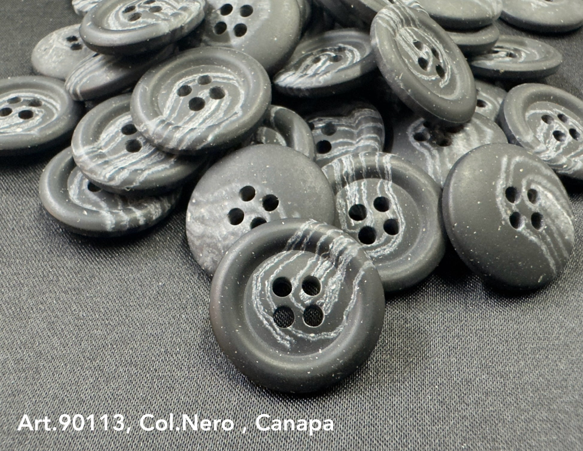 Sustainable Hemp buttons by Buttonology Inc black with white veining and four holes on black fabric