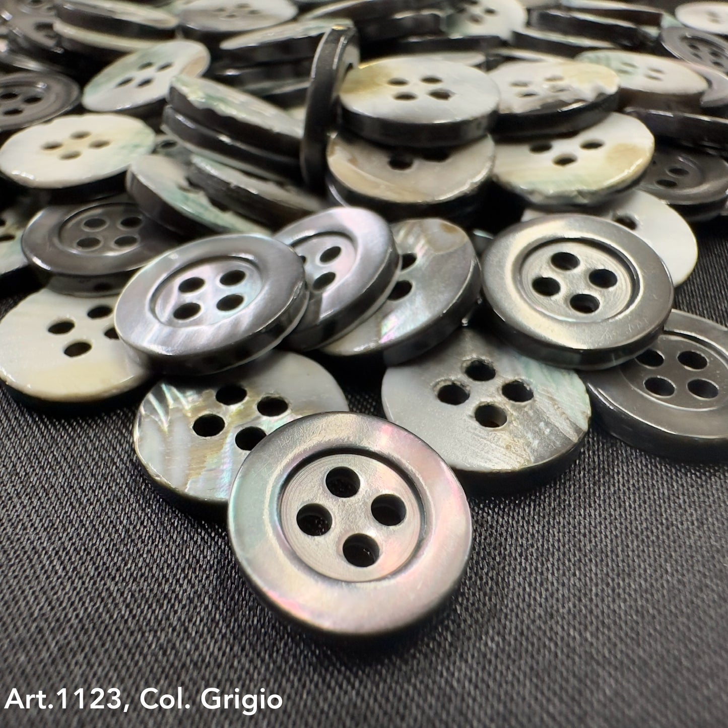 Troca shell buttons by Buttonology Inc in various shades of gray with four holes on black fabric