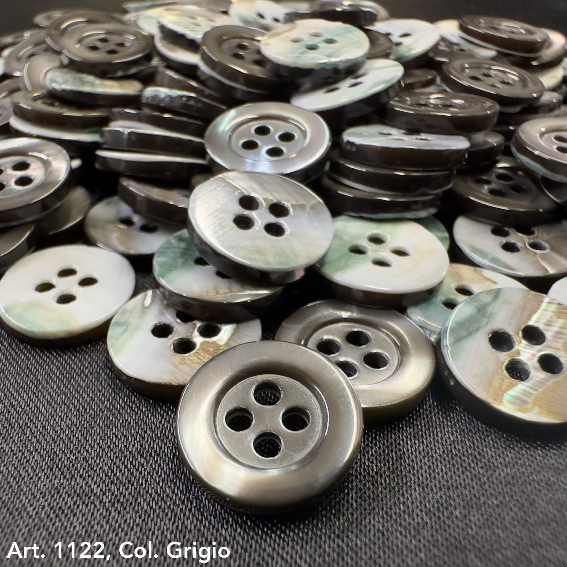 Troca shell buttons by Buttonology Inc in various gray shades stacked on black fabric background