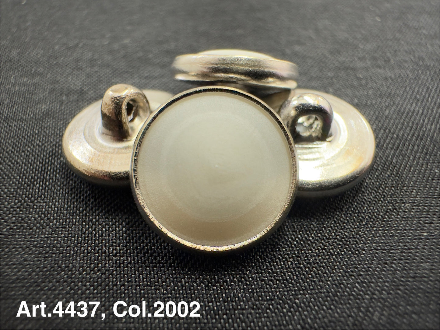 Buttonology Inc urea shank buttons in silver with round smooth surface on black fabric background