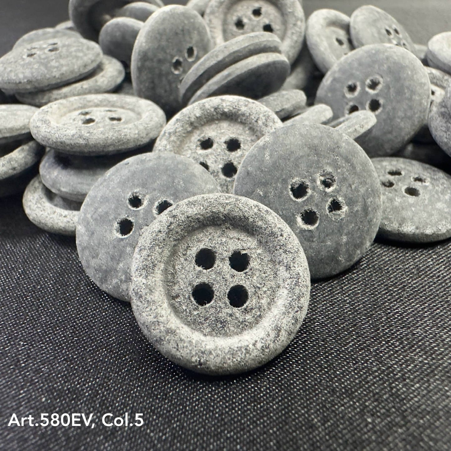 Eco-friendly velvet buttons by Buttonology Inc in gray with a four-hole design on black fabric