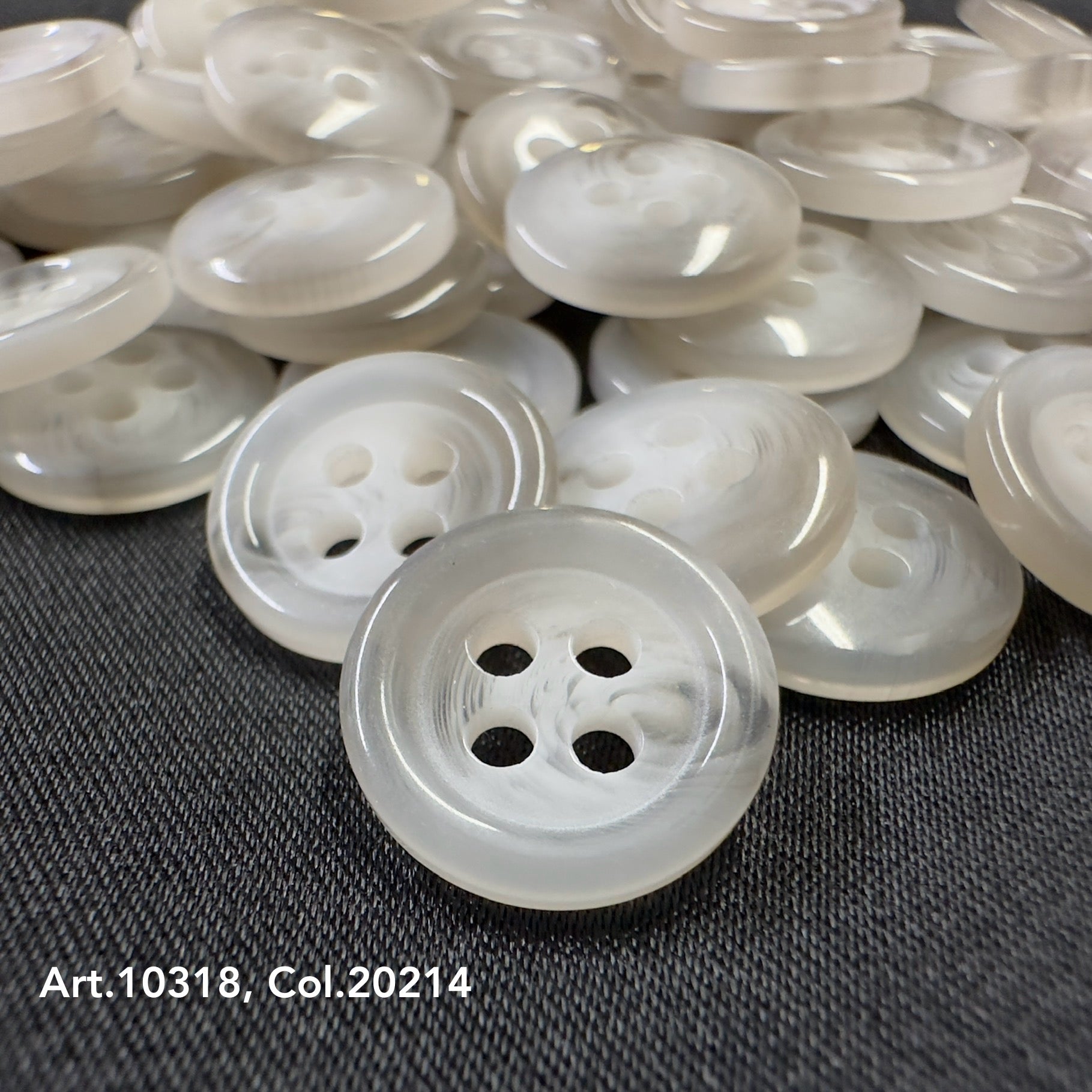 High-quality shirt buttons by Buttonology Inc with a smooth pearly finish on dark fabric background