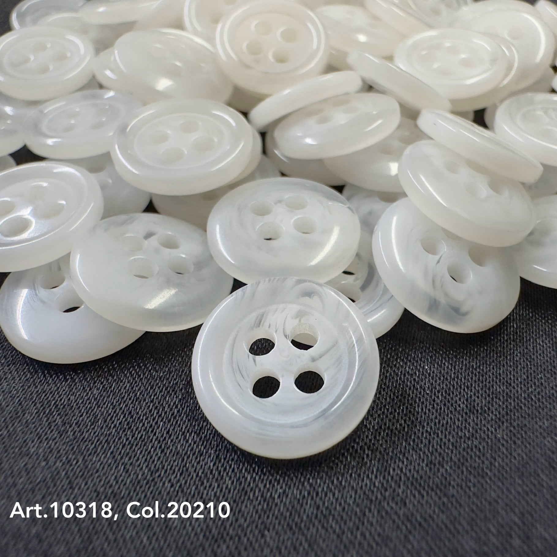 Buttonology Inc white high-quality shirt buttons with four holes stacked on black fabric