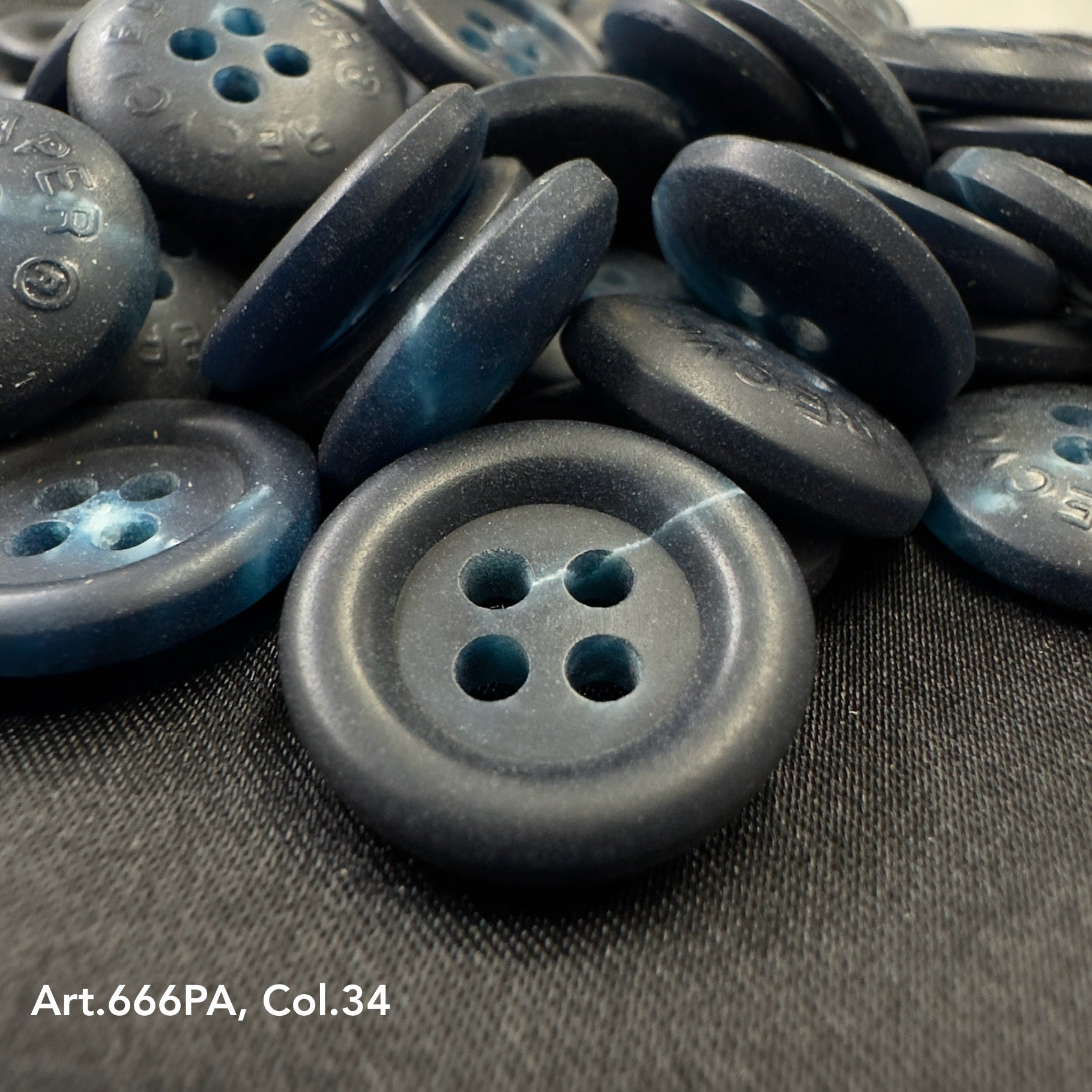 Close-up view of dark blue recycled paper buttons from Buttonology Inc with four holes on black fabric