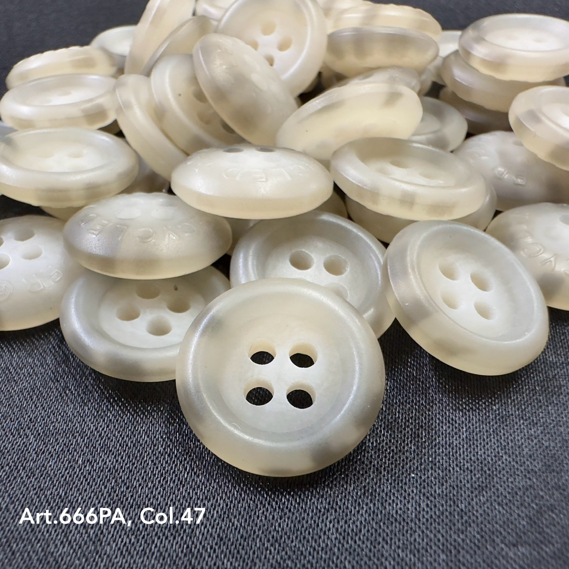 Close-up of translucent recycled paper buttons by Buttonology Inc with four holes on dark fabric background