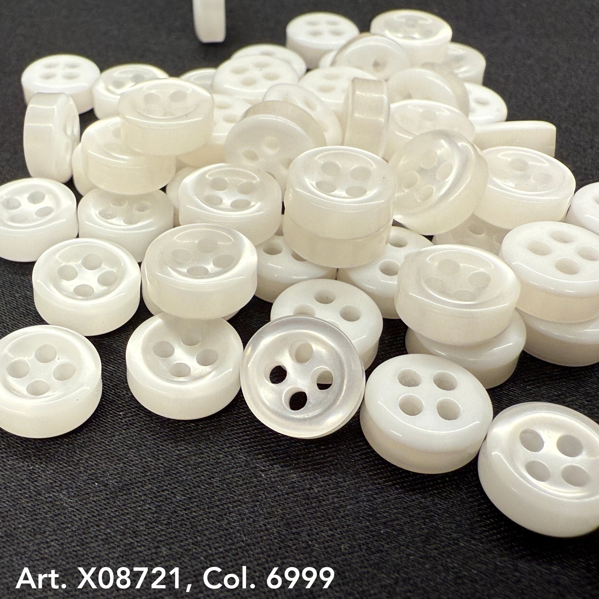 Variety of white round sewing buttons from Buttonology Inc. featuring four holes for versatile use.