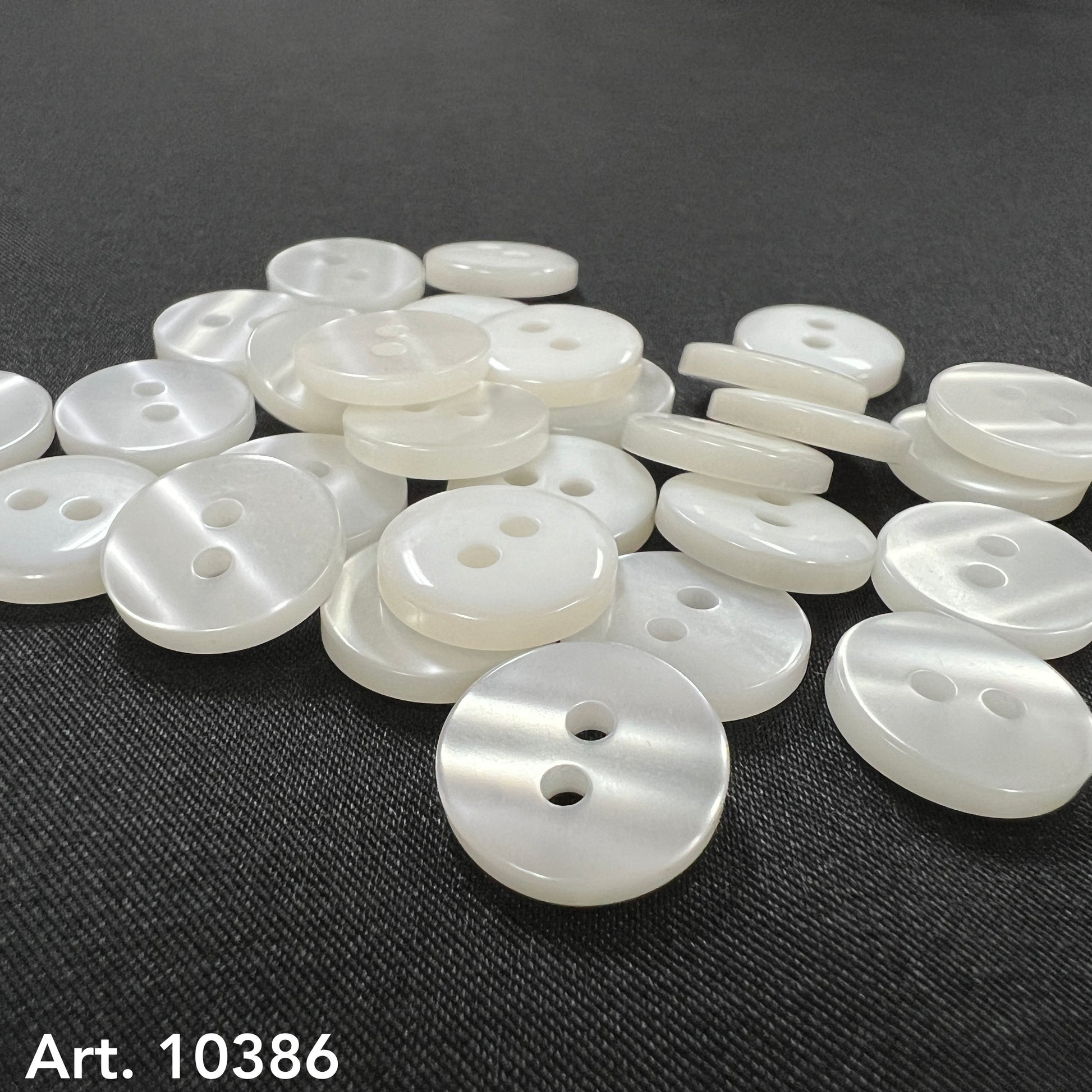 Assorted white two hole sewing buttons on a black background from Buttonology Inc