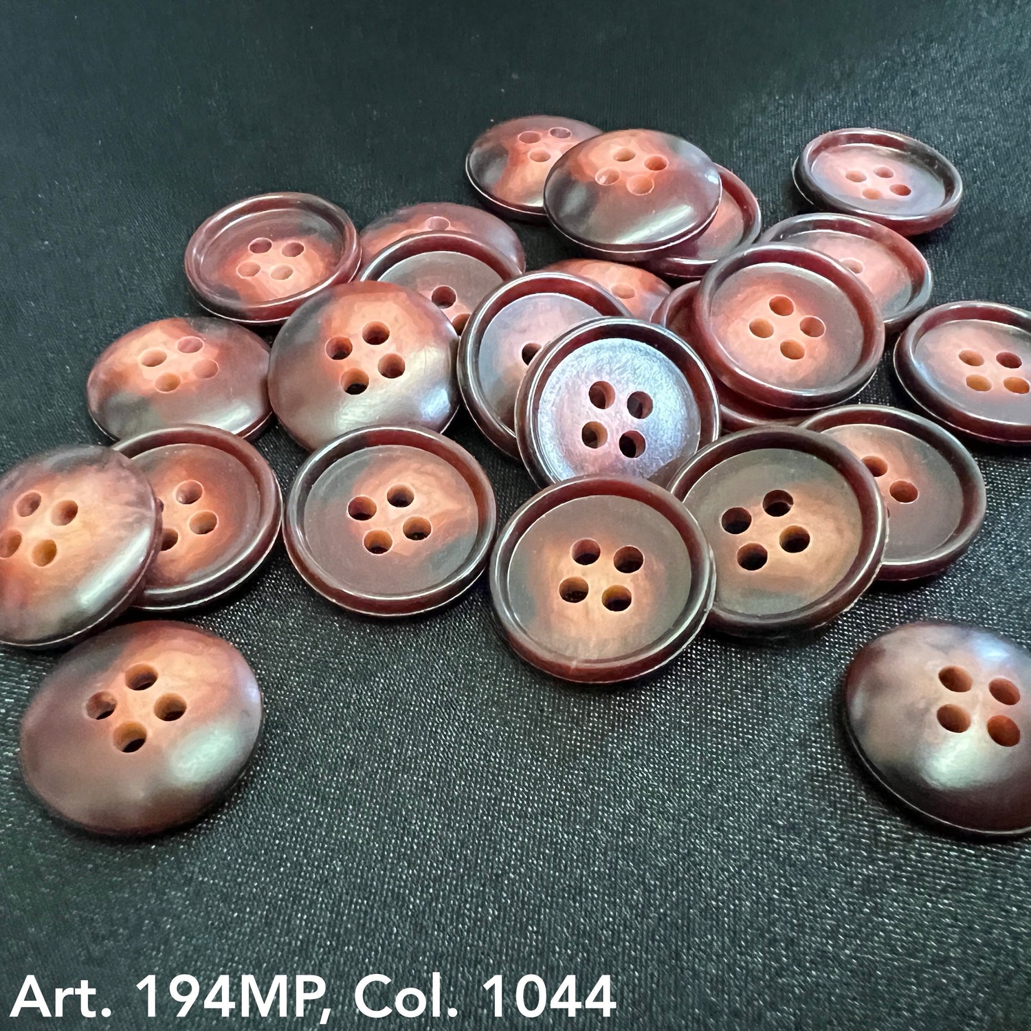 Round brown urea resin buttons wholesale with a polished finish on a dark fabric background