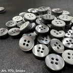 Collection of Smoke 4 hole garment buttons from Buttonology Inc on a black background