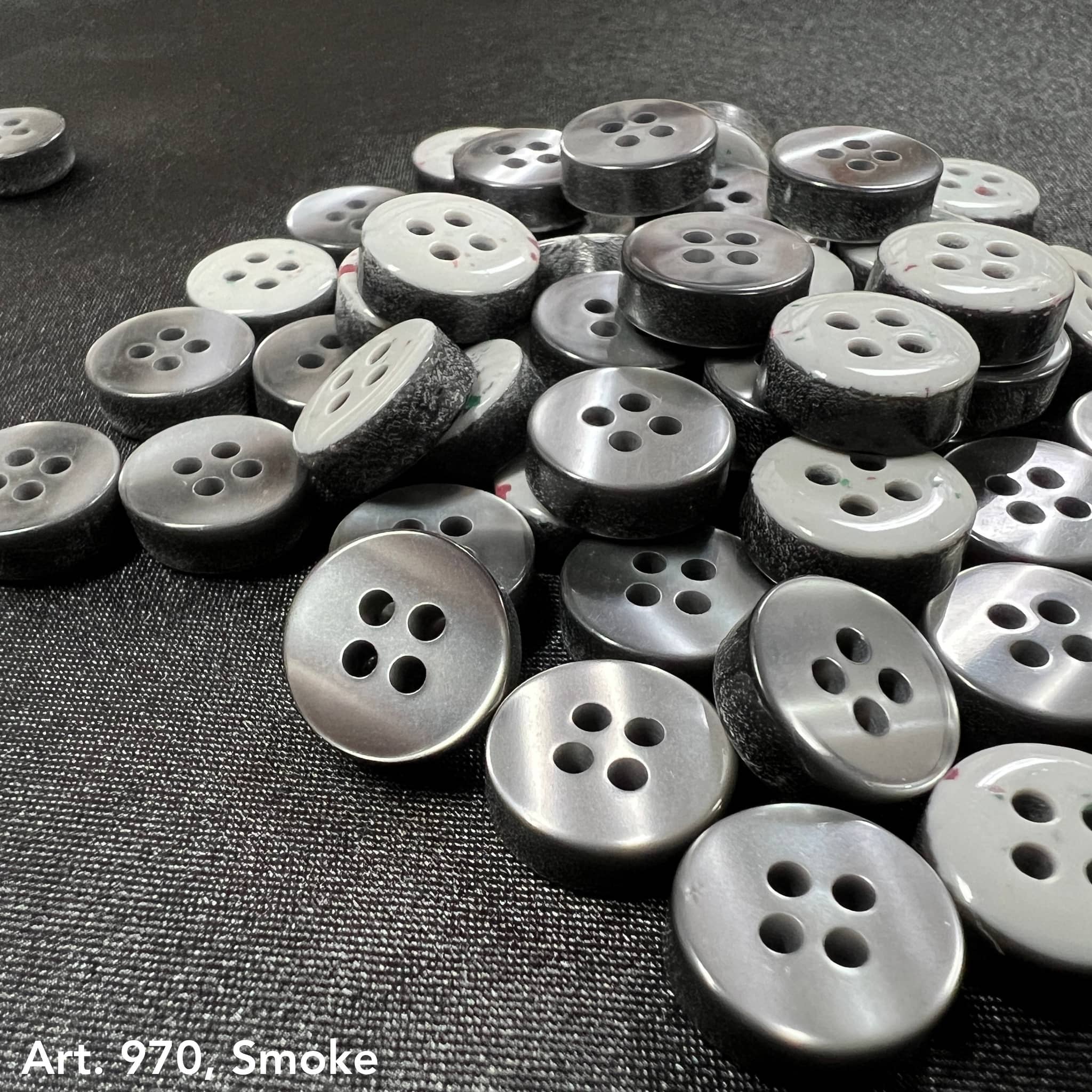 Collection of Smoke 4 hole garment buttons from Buttonology Inc on a black background