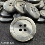 Gray 4-hole plastic buttons by Buttonology Inc stacked on black fabric background