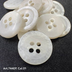 White 4-hole plastic buttons by Buttonology Inc. arranged on a dark fabric background
