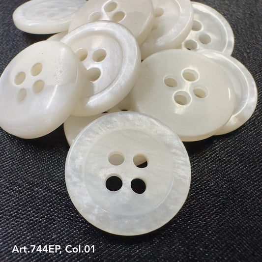 White 4-hole plastic buttons by Buttonology Inc. arranged on a dark fabric background