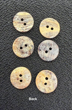 Six round buttons with two holes on a textured black surface