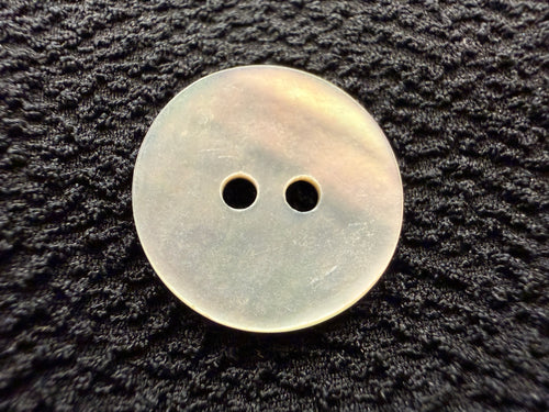 Round button with two holes on a textured black surface