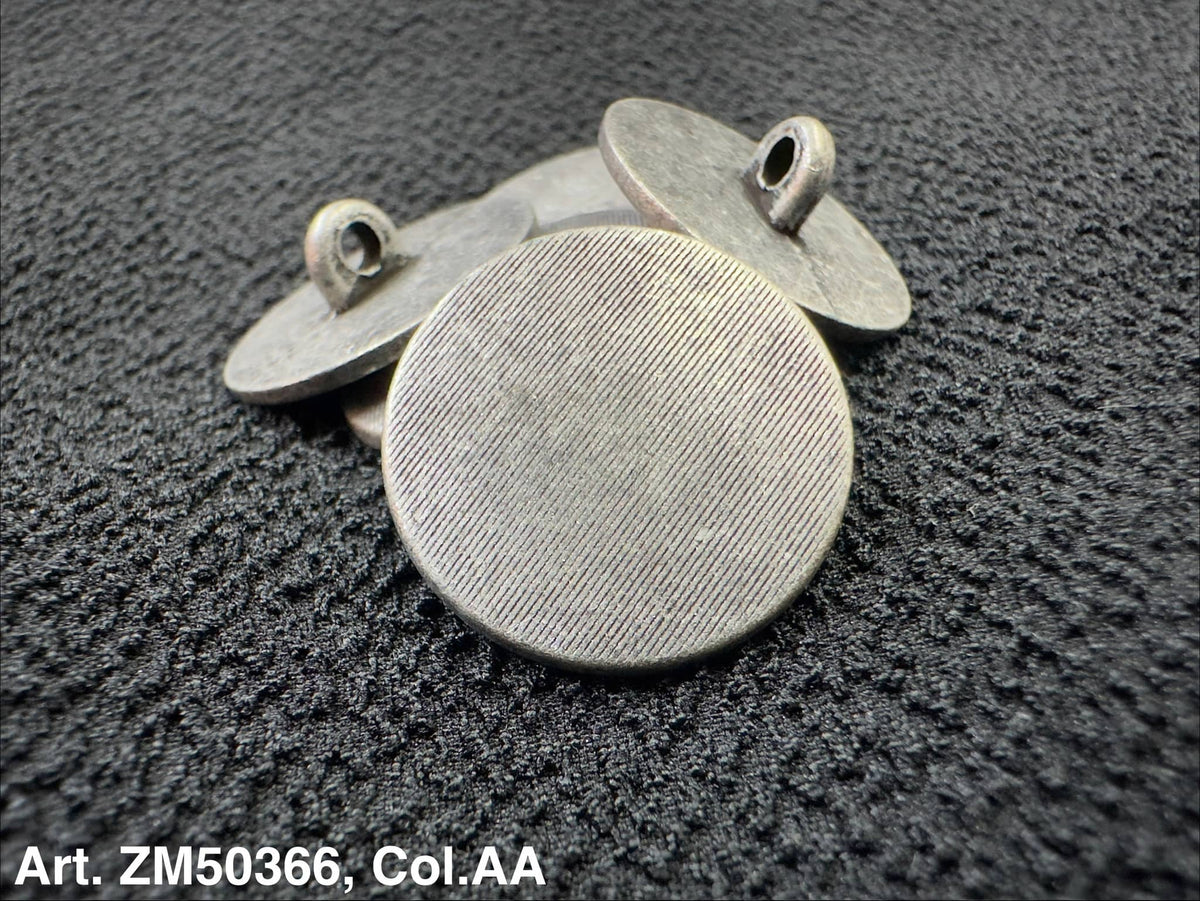 Two metallic round pendants on a textured dark surface
