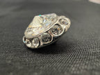 Diamond ring with a large central stone and smaller stones on a black fabric background