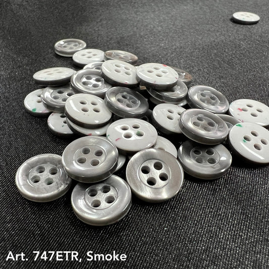 Pile of smoke four-hole buttons by Buttonology Inc on a dark fabric background