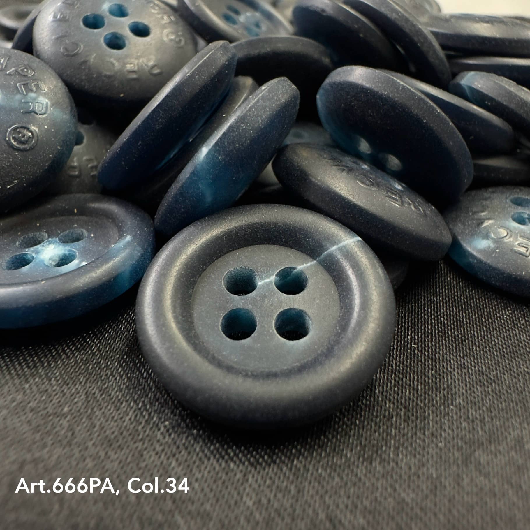 Close-up of dark recycled paper buttons by Buttonology Inc with four holes on black fabric