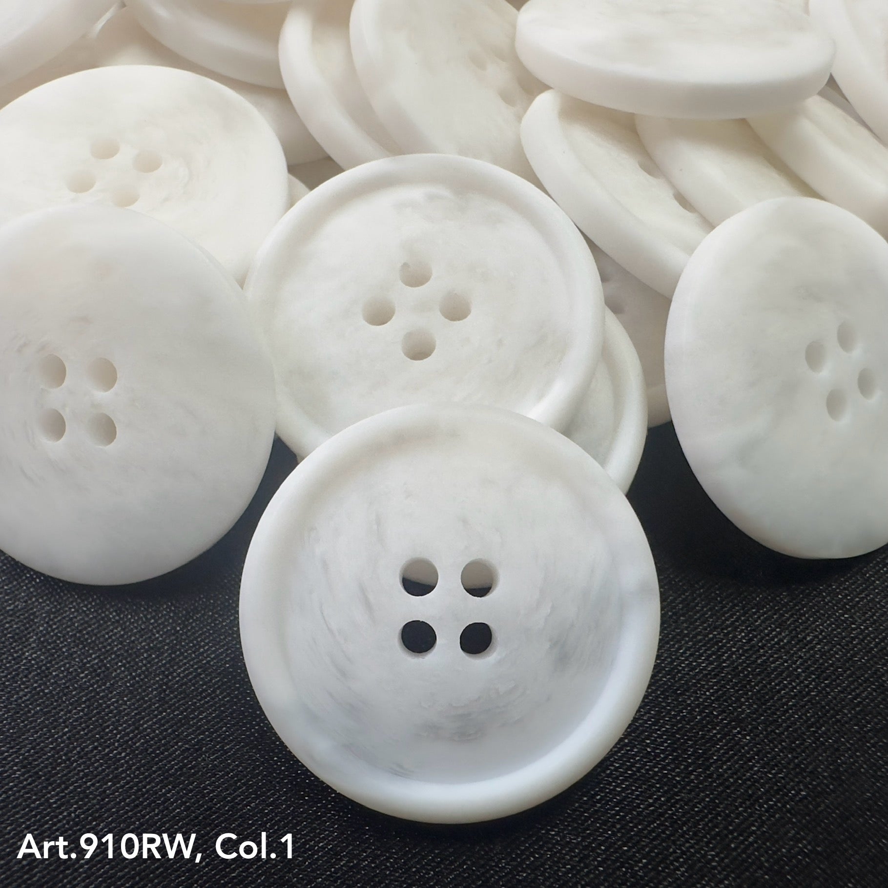 Buttonology Inc white marbled four hole round coat buttons for sewing stacked on dark fabric background