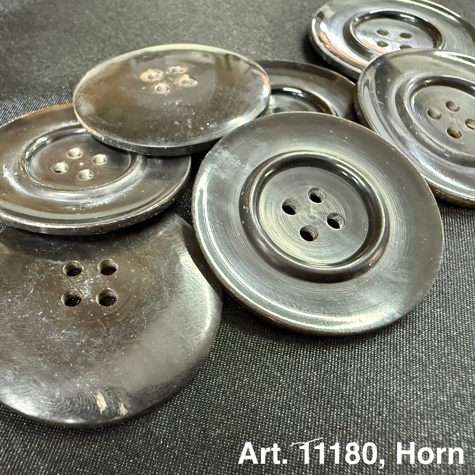 Dark glossy natural horn sewing button set showing four hole large vintage style buttons on black fabric