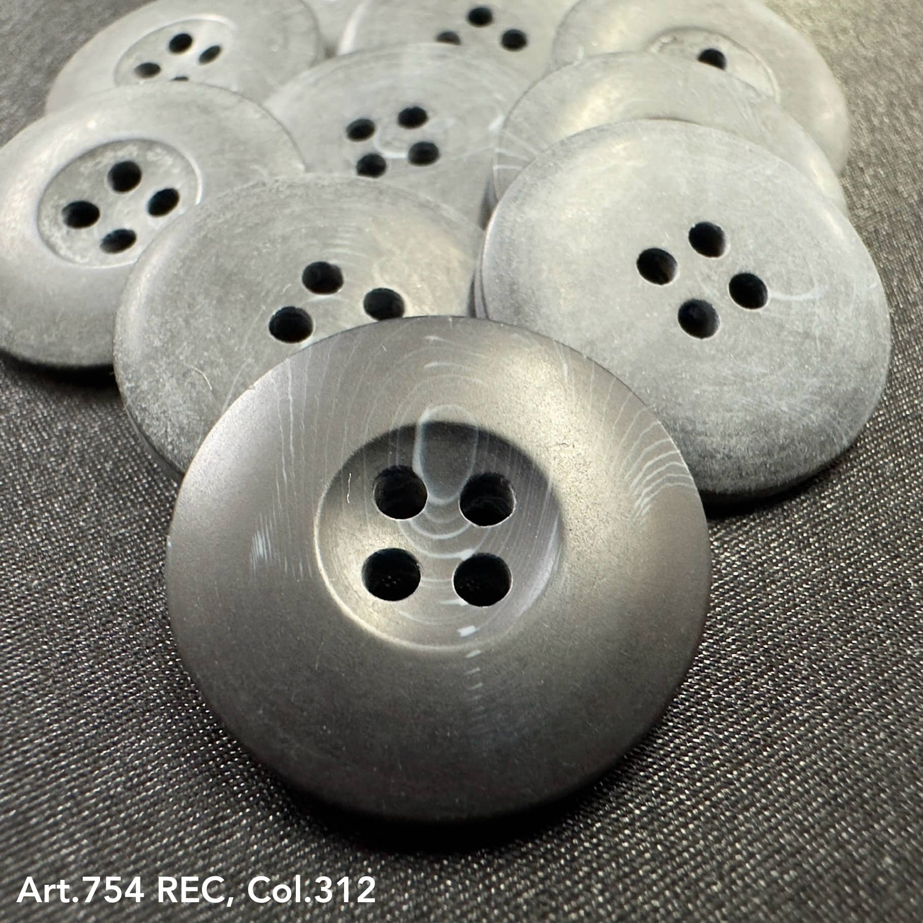 Gray round buttons with four holes showcasing custom button designs by Buttonology Inc