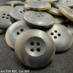 Gray buttons with four holes stacked on black fabric showcasing custom button designs by Buttonology Inc