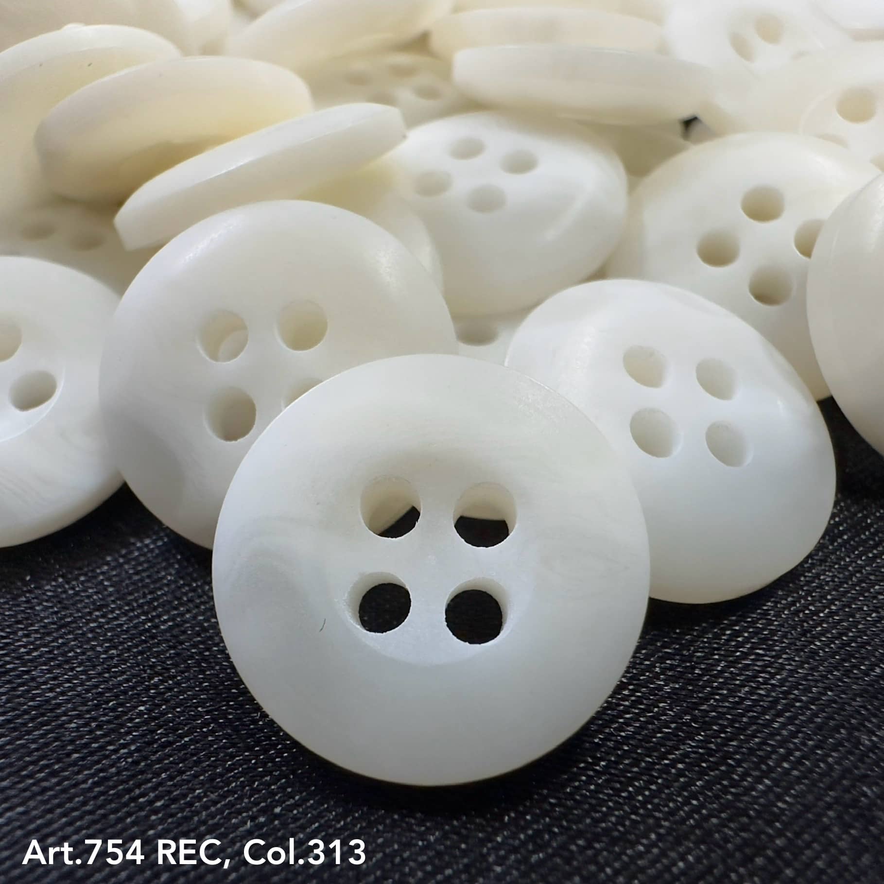 White buttons with four holes on black fabric showcasing custom button designs by Buttonology Inc