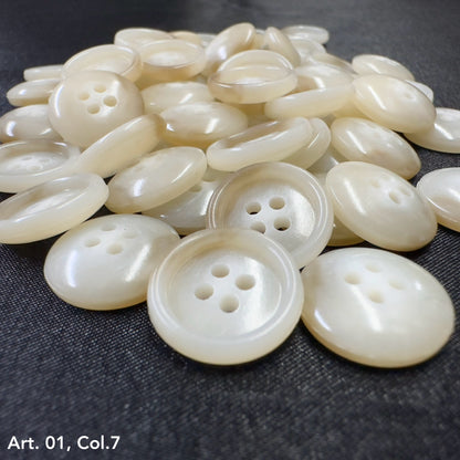 Buttonology Inc pearl white four hole round buttons piled on dark fabric premium shirt buttons for sewing