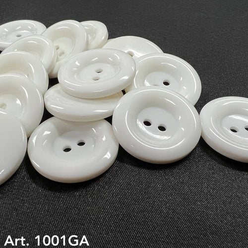 White glossy two hole round buttons on dark fabric by Buttonology Inc white garment buttons for sewing projects