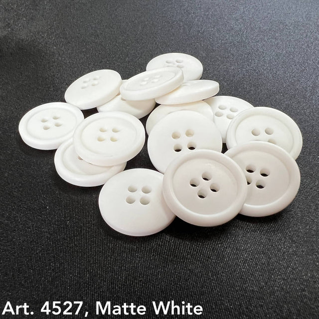 Basic white 4-hole buttons by Buttonology Inc scattered on black fabric background