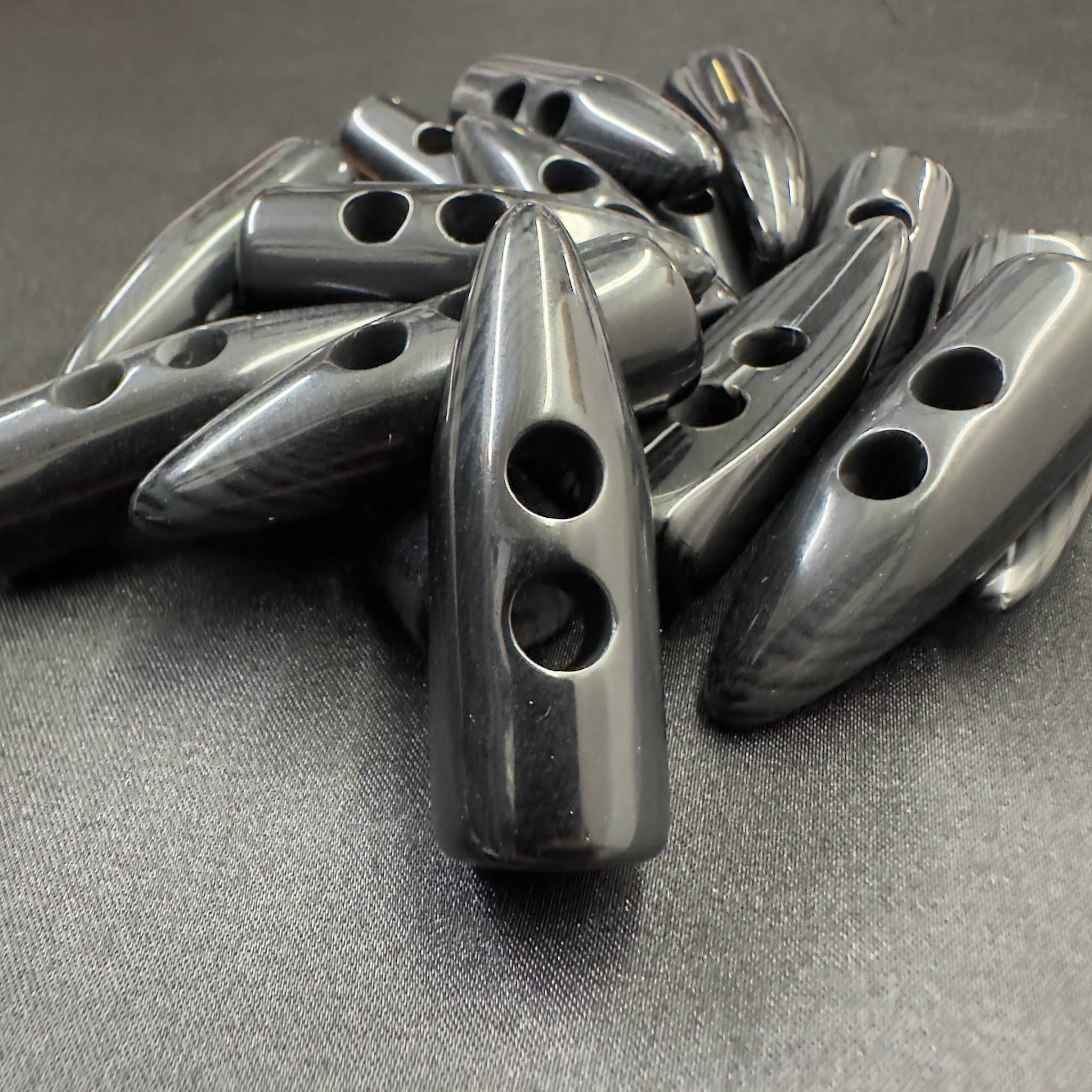 Black toggle buttons from Buttonology Inc with two holes on a black surface