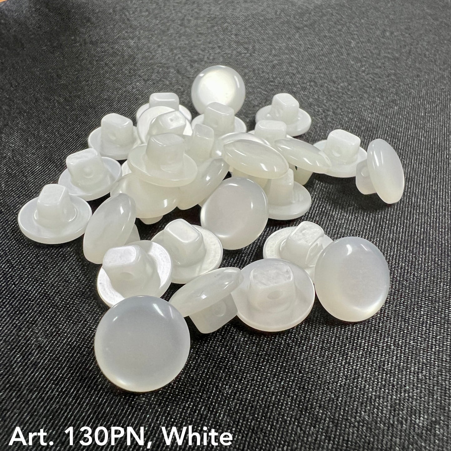 White buttons from Buttonology Inc for button sewing supplies on dark fabric background