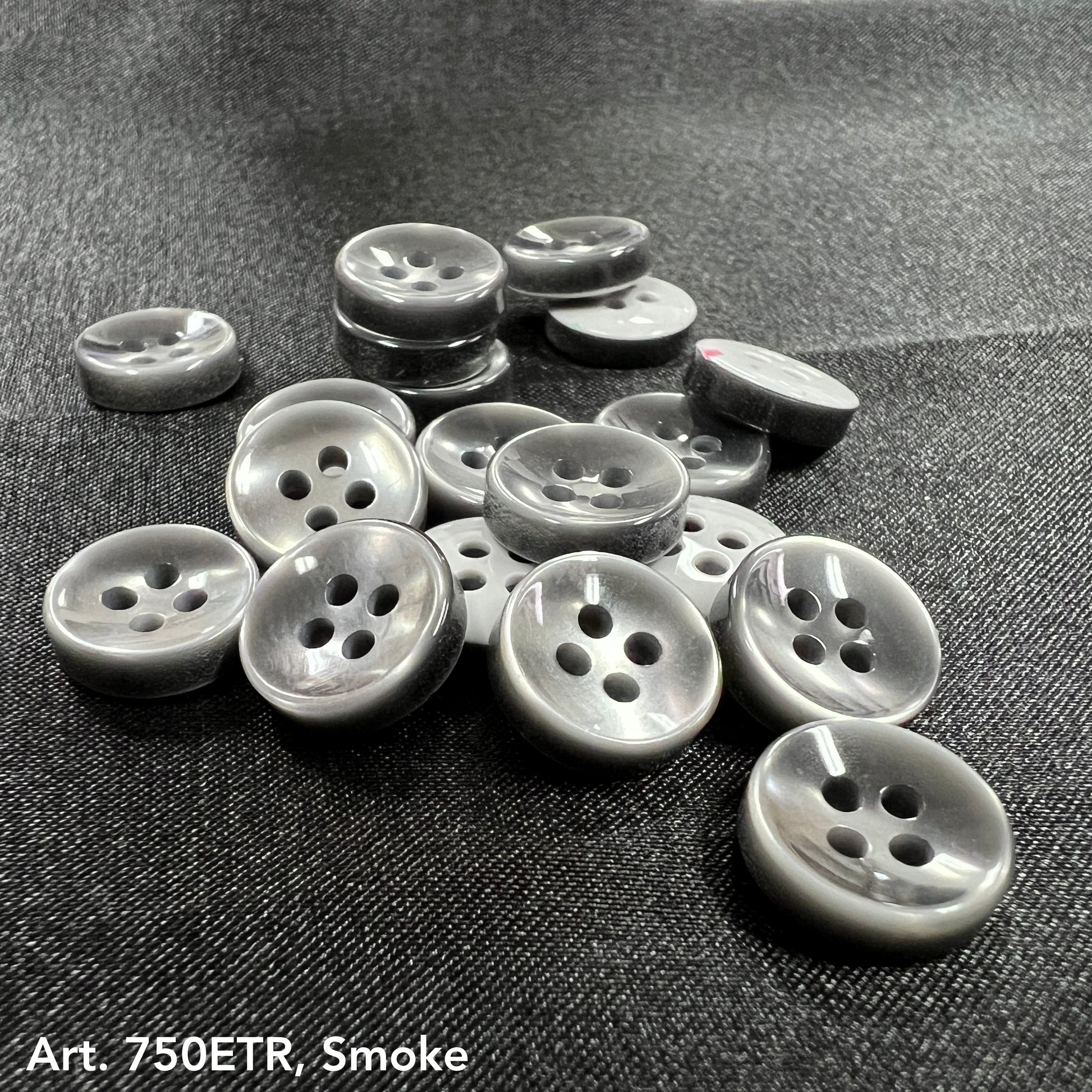 Buttonology Inc grey smoke four hole round buttons on black fabric pile for wholesale button supplies