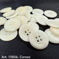 White Corozo buttons scattered on black fabric by eco-friendly button supplier Buttonology Inc