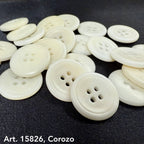 White Corozo buttons scattered on black fabric by eco-friendly button supplier Buttonology Inc
