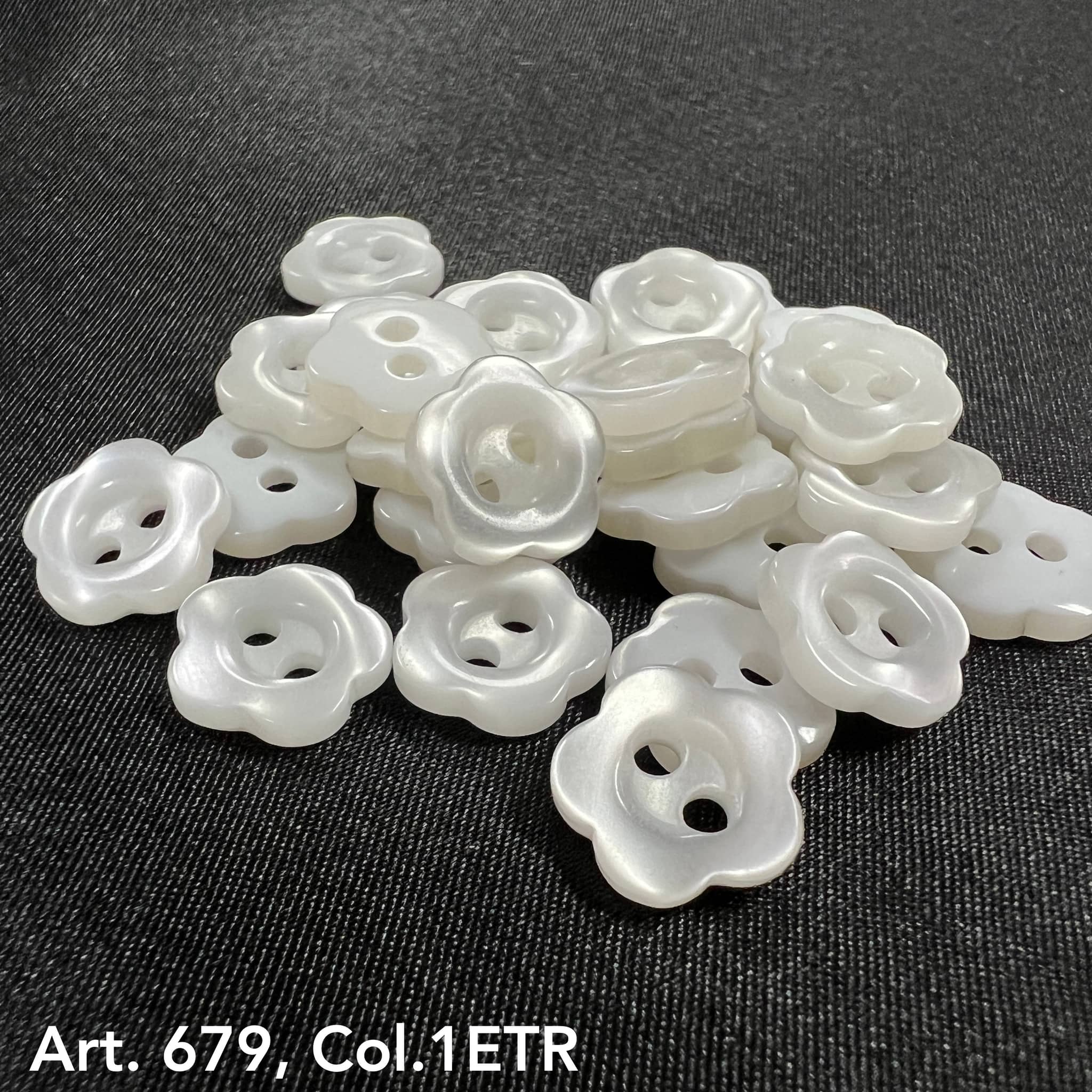 Assorted white flower-shaped garment buttons in various sizes on a black background