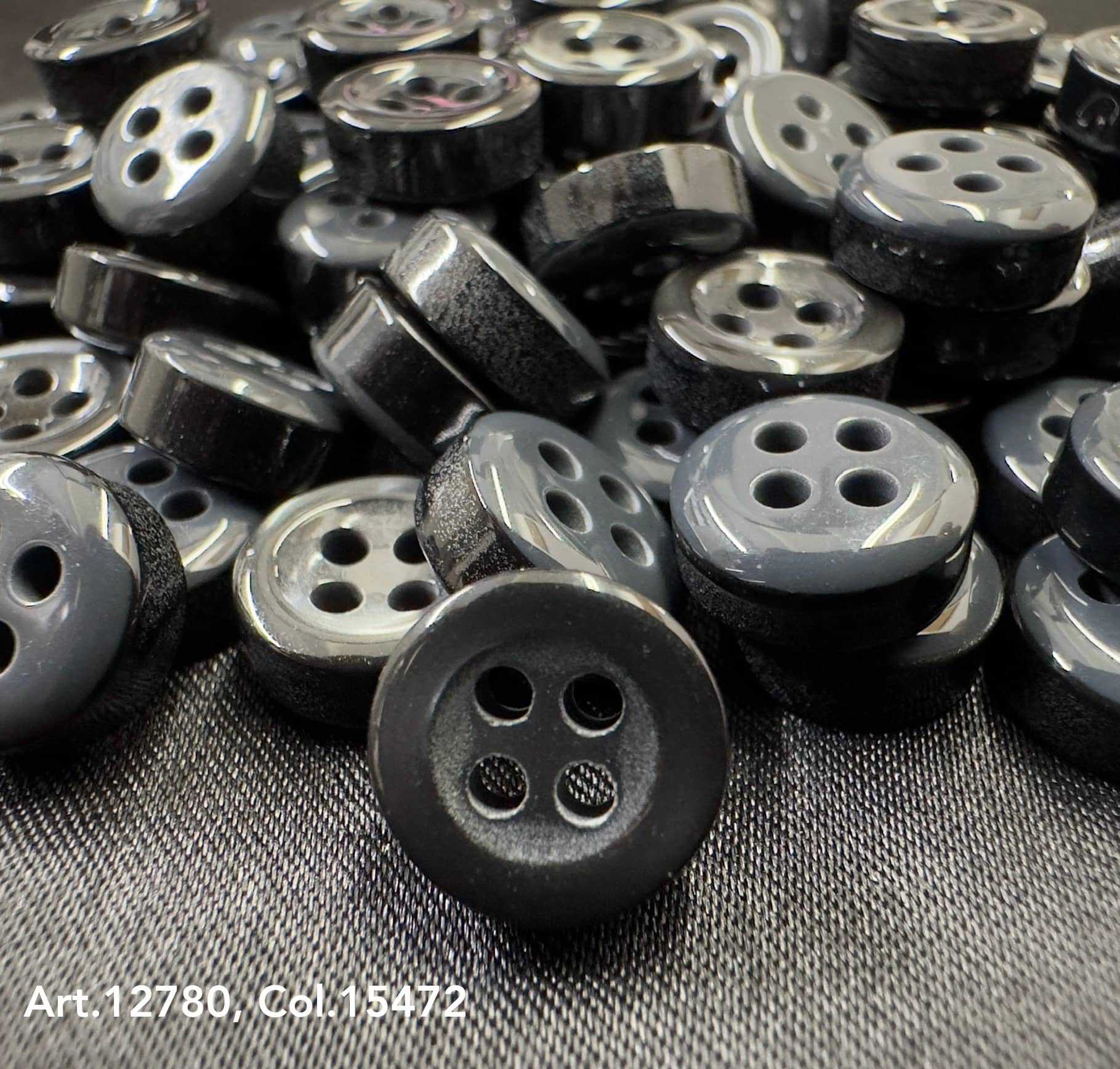 Close-up view of 18L four hole plastic buttons from Buttonology Inc. in black and gray colors