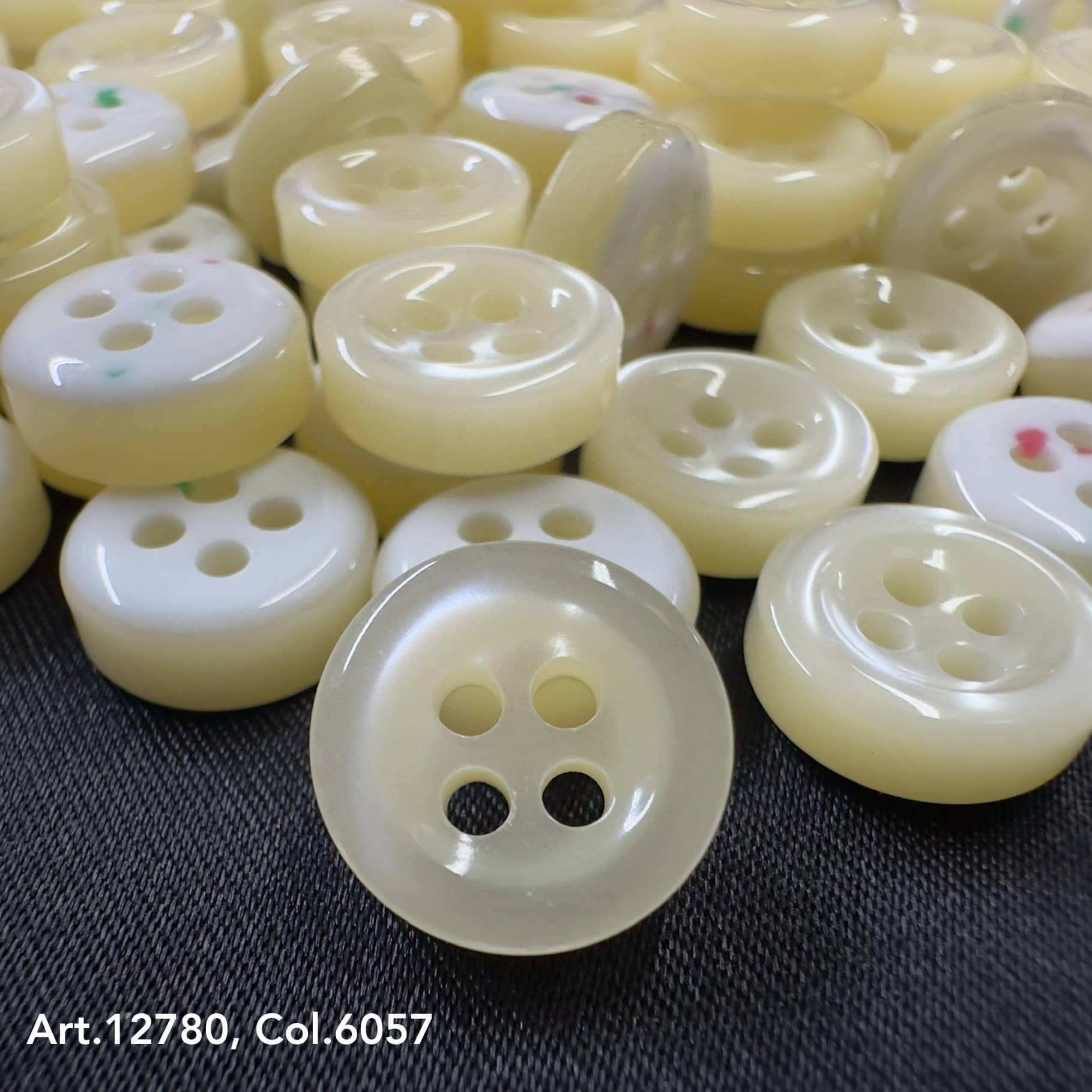 18L four hole plastic buttons in cream color by Buttonology Inc, glossy finish close-up