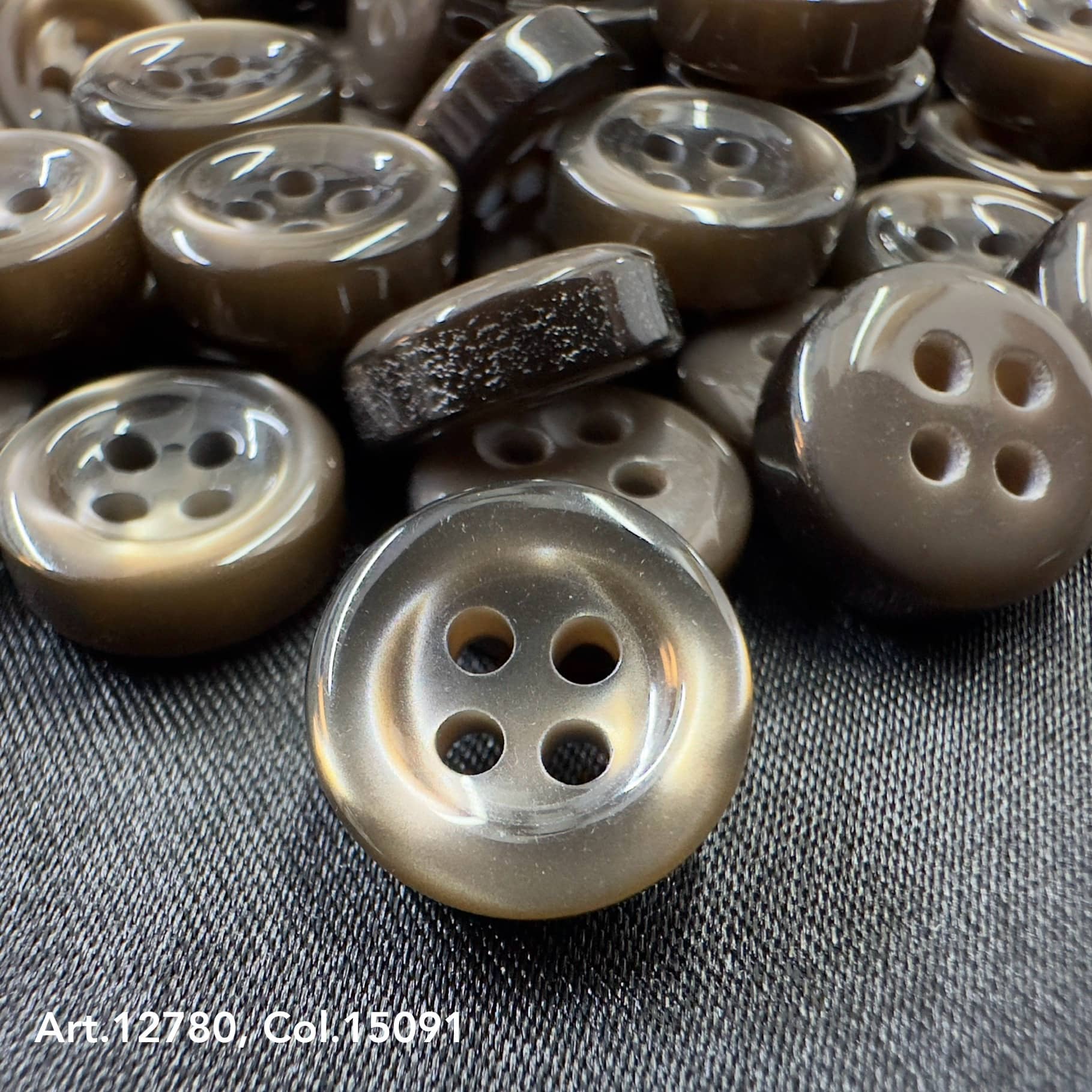 18L four hole plastic buttons in brown shade by Buttonology Inc displayed on fabric